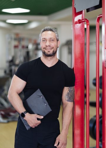 daily-sport-routine-healthy-lifestyle-gray-haired-smiling-coach-man-portrait-in-the-gym.jpg